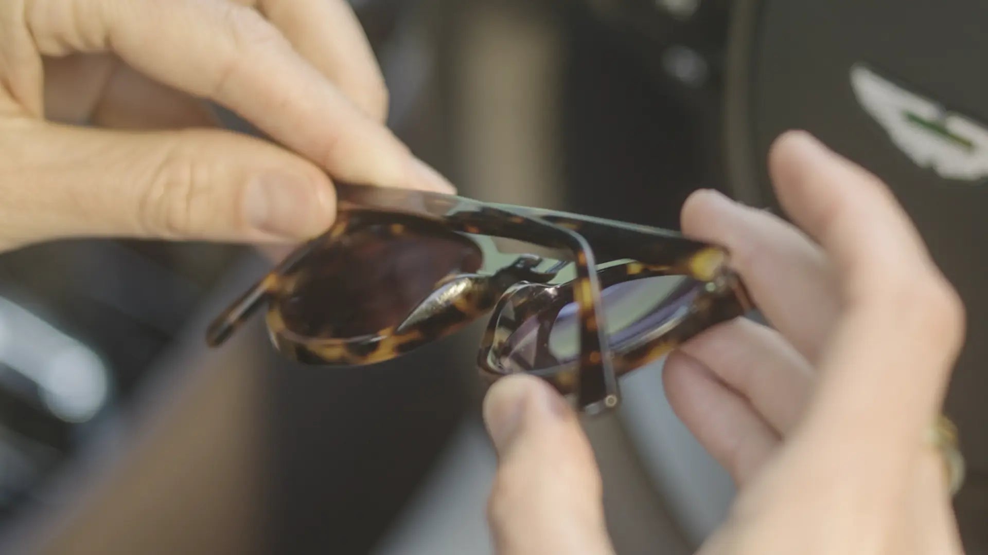 Hands holding a pair of Yoovy sunglasses